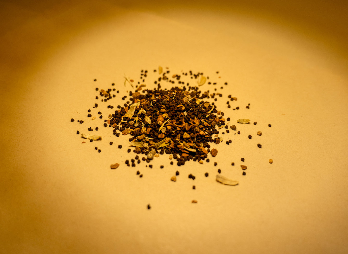 A variety of spices including cinnamon, cardamom, cloves, ginger, and black pepper scattered on a surface
